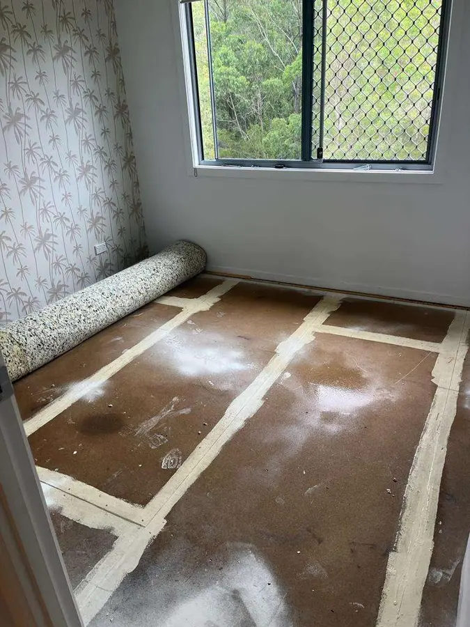Bedroom with the carpet rolled up and the tack strip exposed for drying